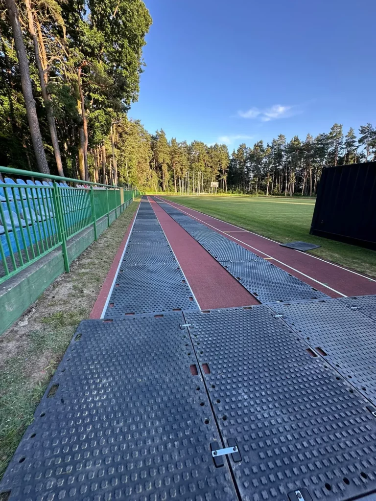 Pas z płyt drogowych wyznaczający przejazd po bieżni stadionu w Złocieńcu